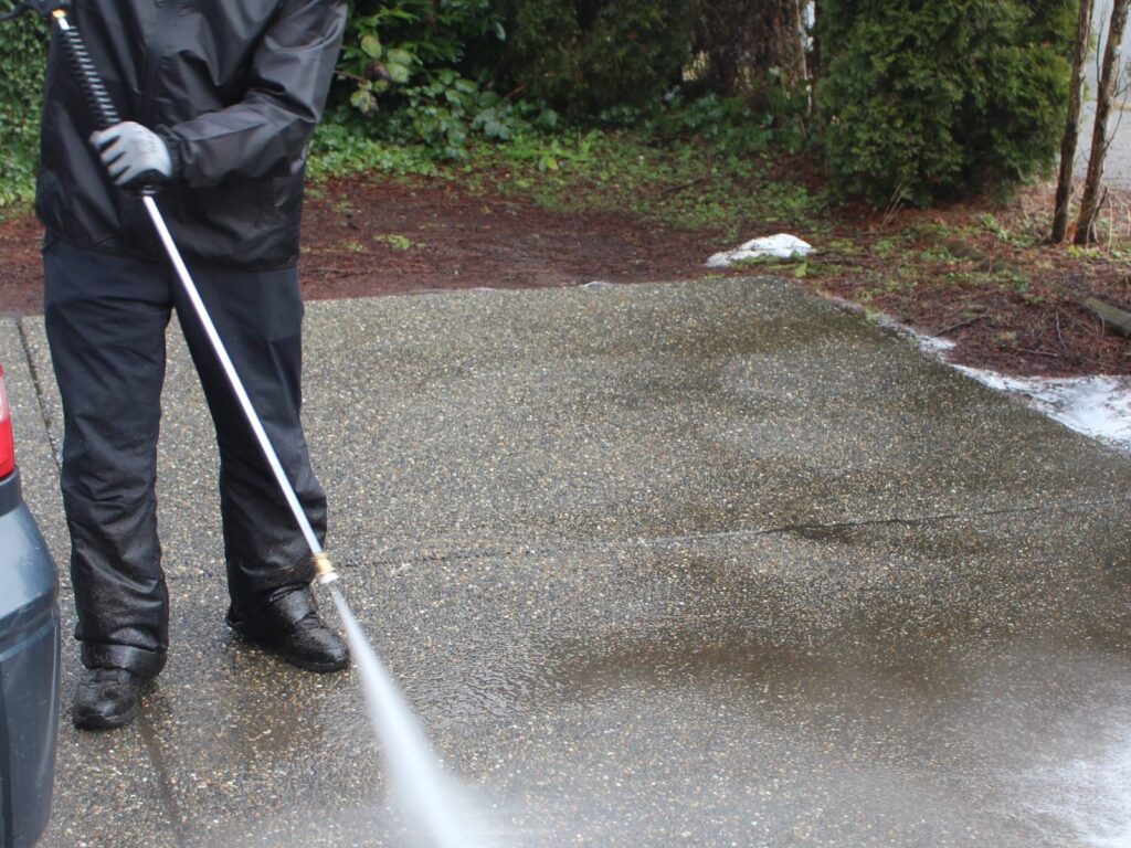 Pressure washing a driveway, with a clean strip next to dirty concrete