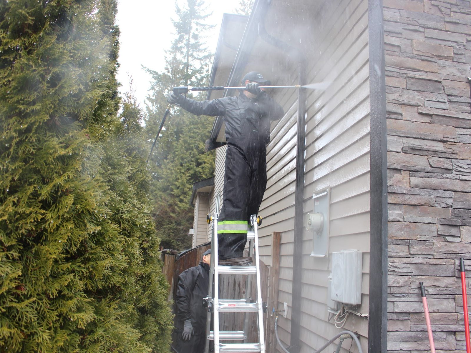 Cleany X washing house siding from a ladder